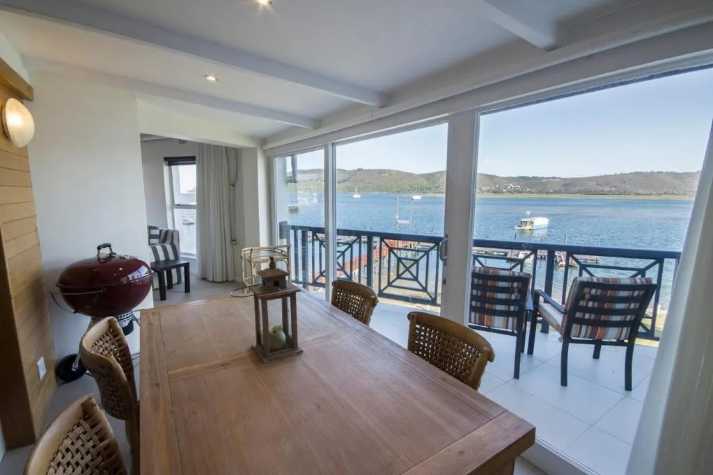 Waterfront deck with dining table, braai, and lagoon views