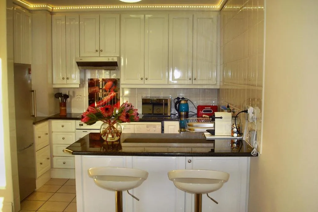 Modern kitchen with white cabinetry, black countertop, and breakfast bar seating
