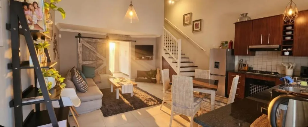Open-plan lounge with sofa, dining area, and kitchen visible in background