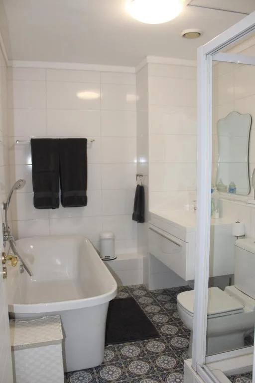 Clean white bathroom with freestanding tub, shower enclosure, and patterned floor tiles
