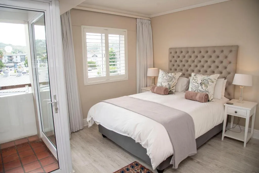 Spacious bedroom with queen bed, upholstered headboard, and scenic lagoon views