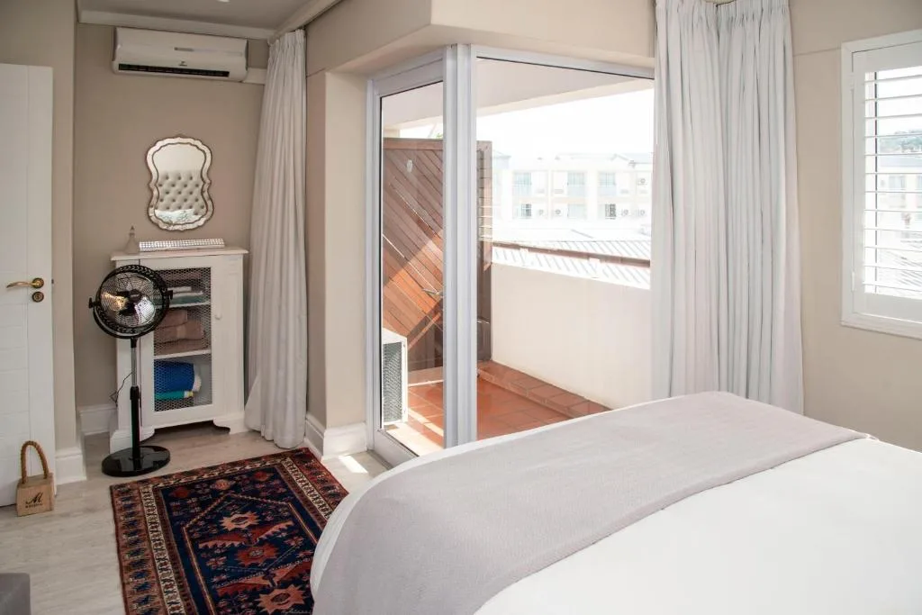 Bright bedroom with white bedding, glass doors opening to wooden deck