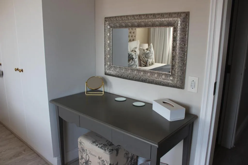 Bedroom vanity with ornate mirror, round magnifying mirror, and decorative items