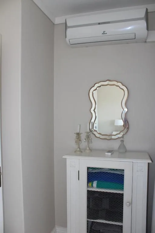 Bedroom corner with decorative mirror, air conditioning unit, and storage cabinet