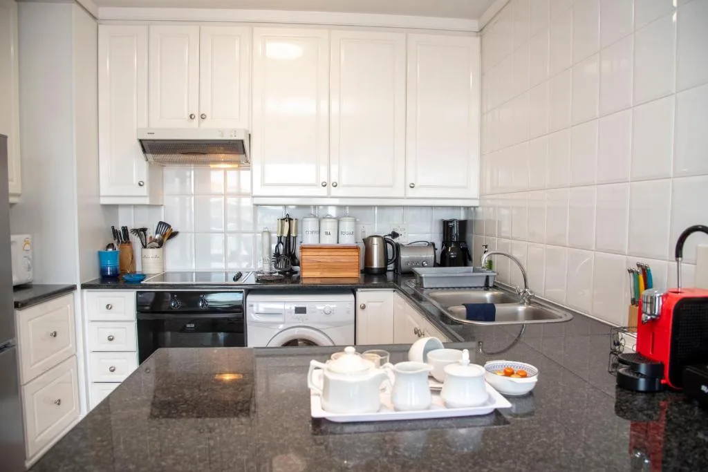 Modern white kitchen with black countertops, stove, and washing machine appliances