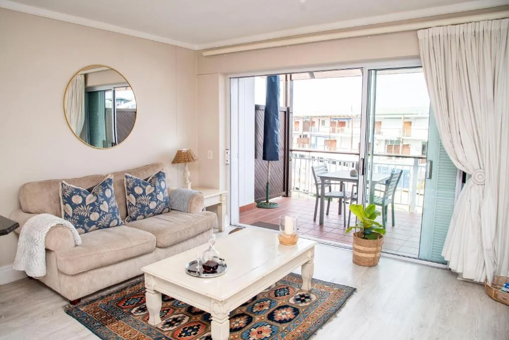 Bright living room with cream sofa, patterned cushions, and deck access