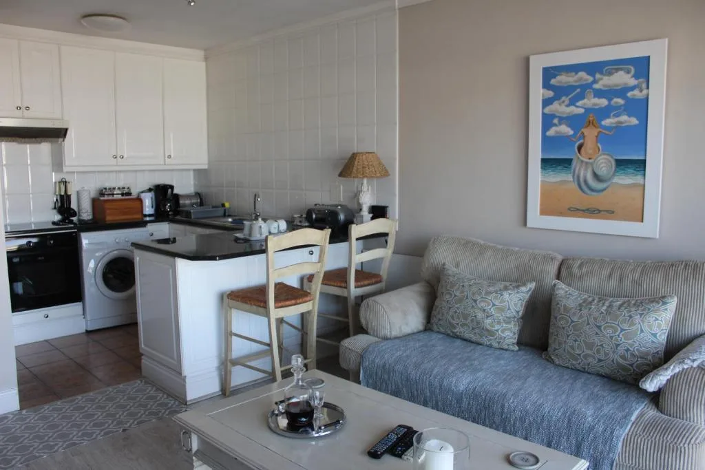 Open-plan lounge with striped sofa, cushions, and coastal artwork on wall