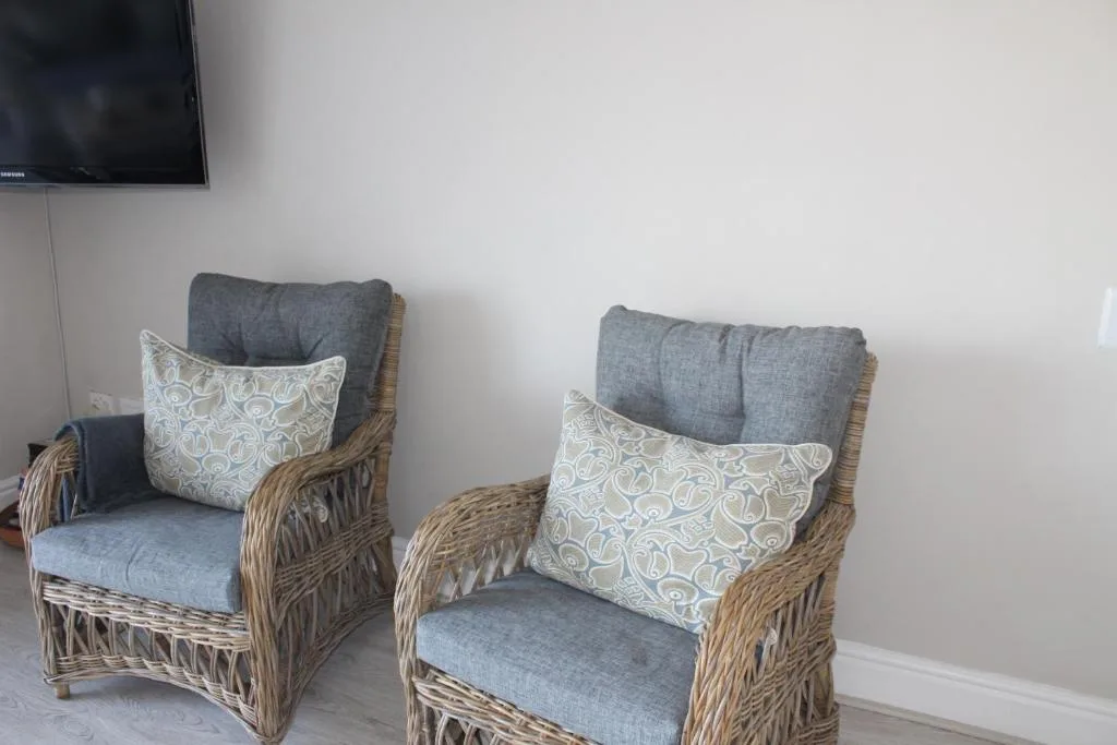 Two wicker armchairs with gray cushions and patterned pillows in a bright lounge area