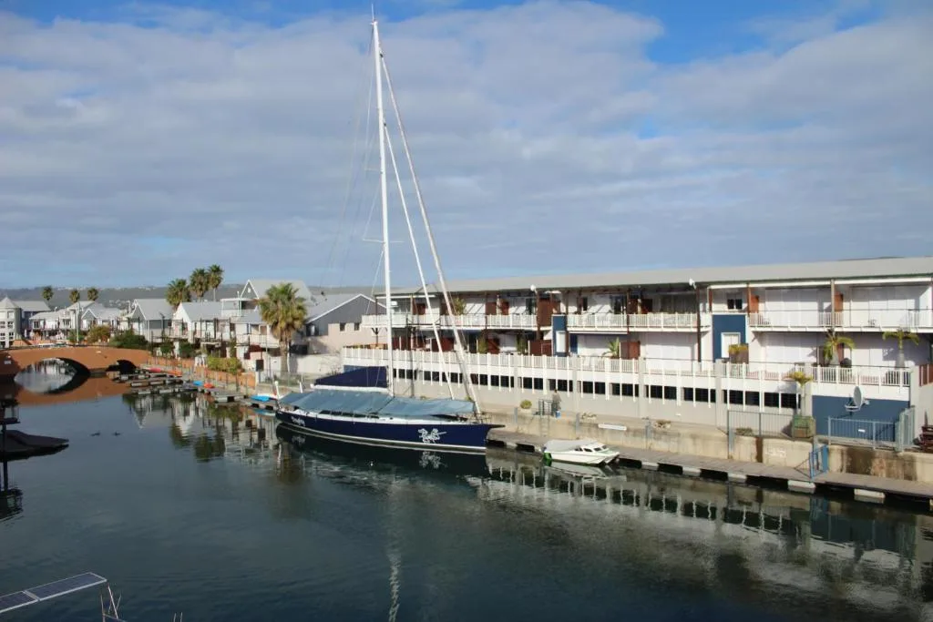Waterfront marina view with sailboat docked beside modern apartments
