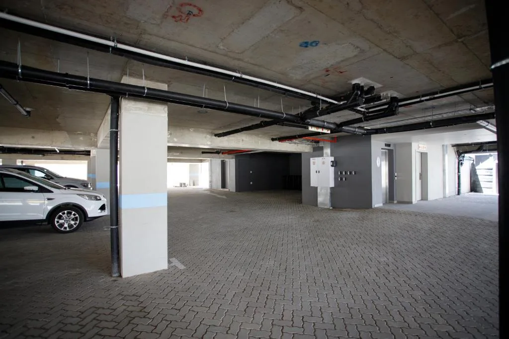 Covered parking garage with white vehicle and concrete pillars