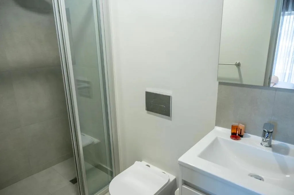 Modern bathroom with glass shower enclosure, white toilet, and vanity sink