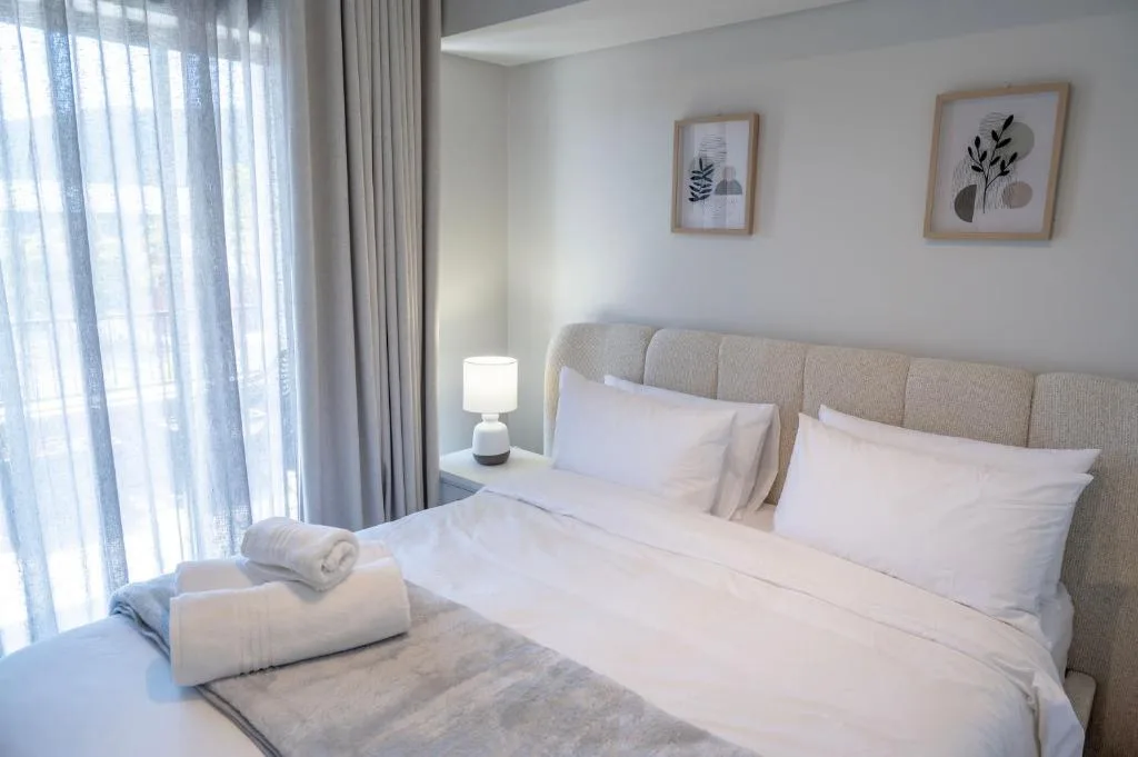 Bright modern bedroom with double bed, neutral décor, and large windows