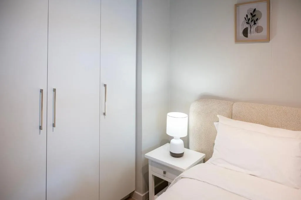 Modern bedroom with bed, bedside lamp, and built-in white wardrobes