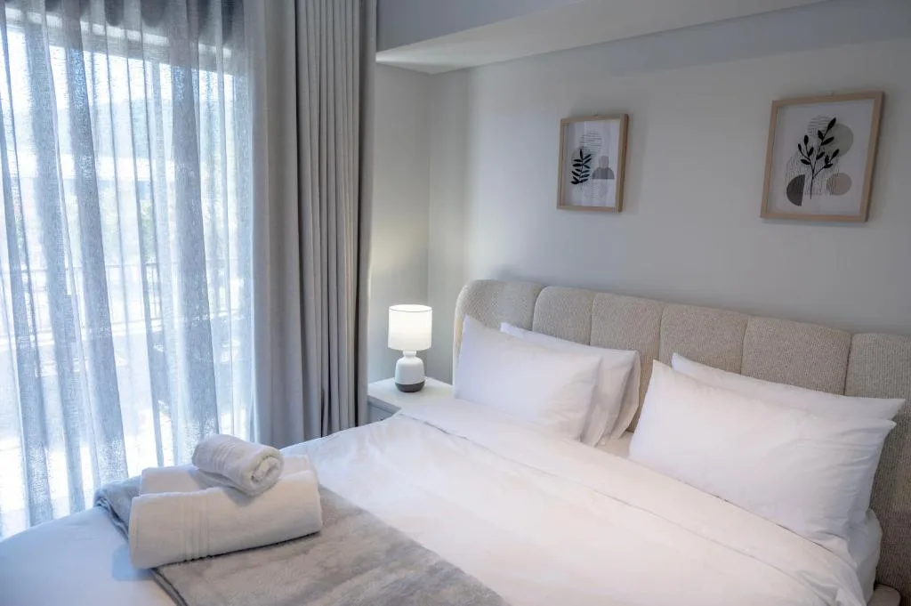 Bright modern bedroom with double bed, neutral bedding, and garden views