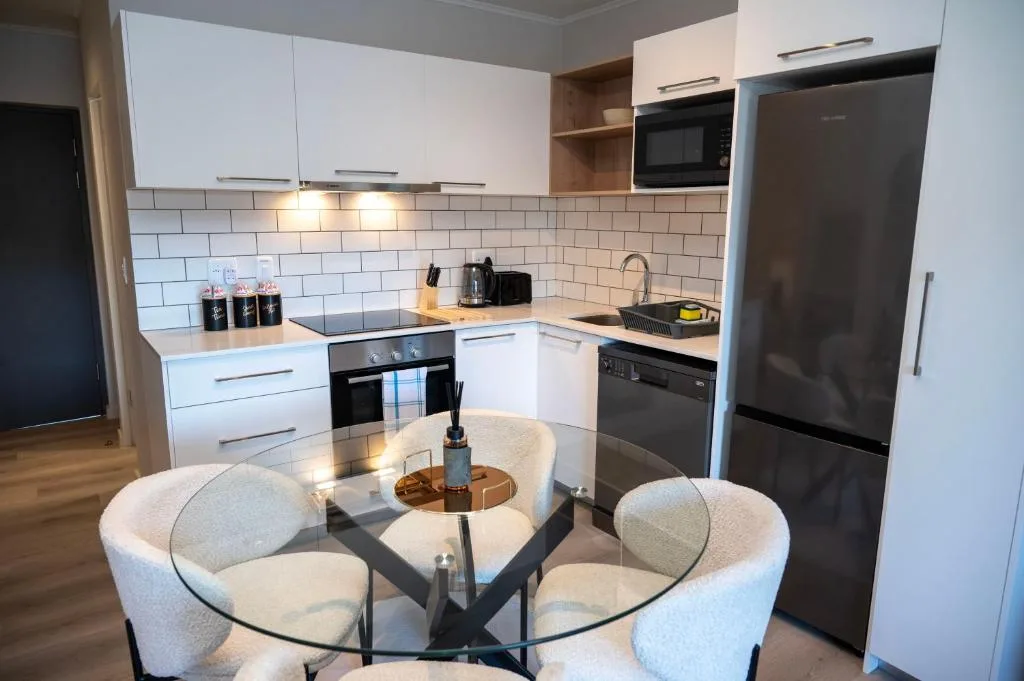 Modern open-plan kitchen with white cabinetry, subway tile backsplash, and black appliances