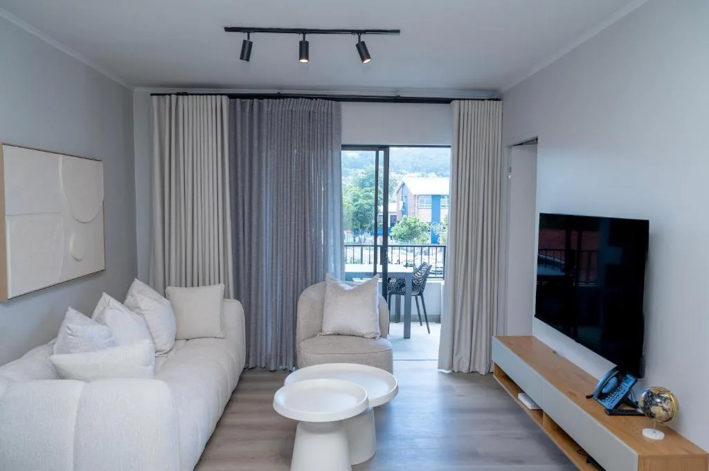 Modern lounge with cream sofa, TV, and ocean view through glass doors