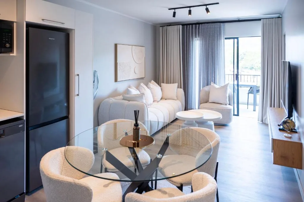 Modern lounge with sofa, armchairs, and glass dining table overlooking balcony