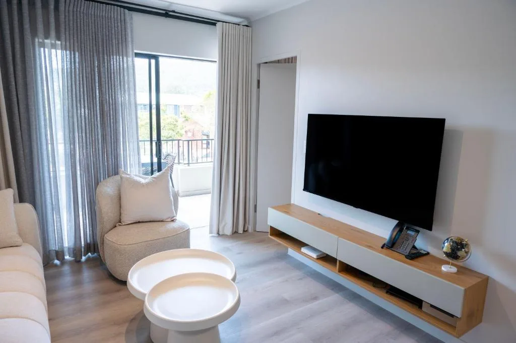 Modern lounge with TV, comfortable seating, and balcony access with views