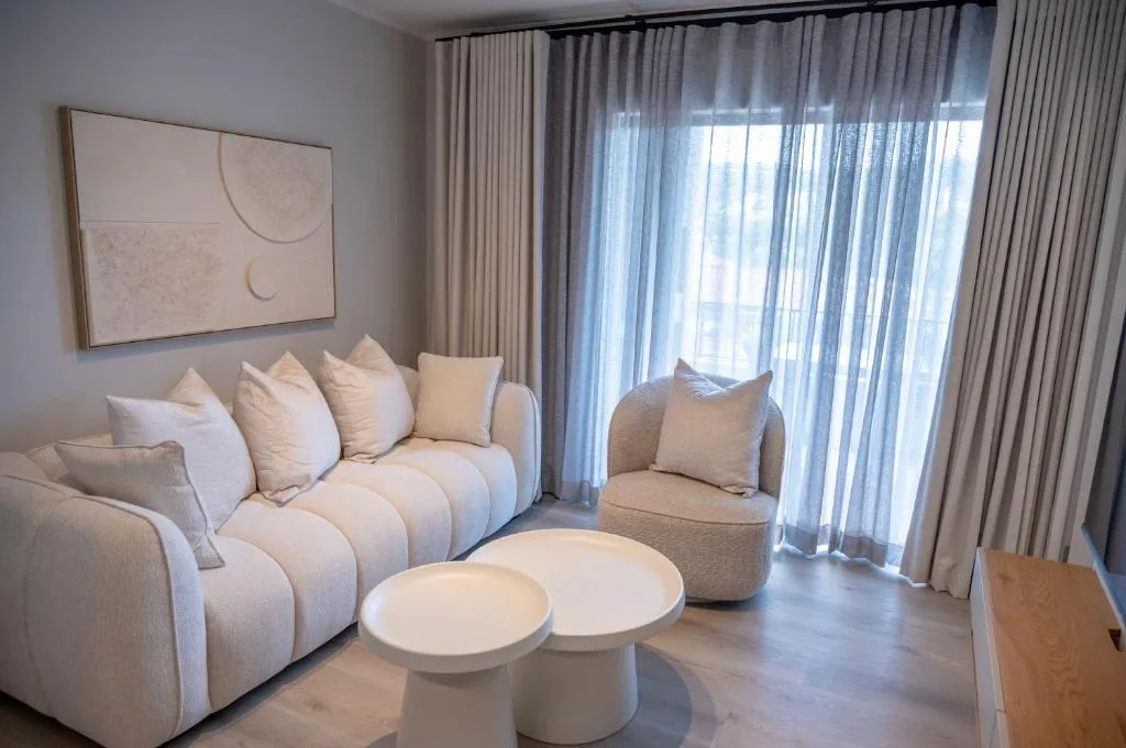Modern living room with cream sofa, armchair, and minimalist white coffee tables