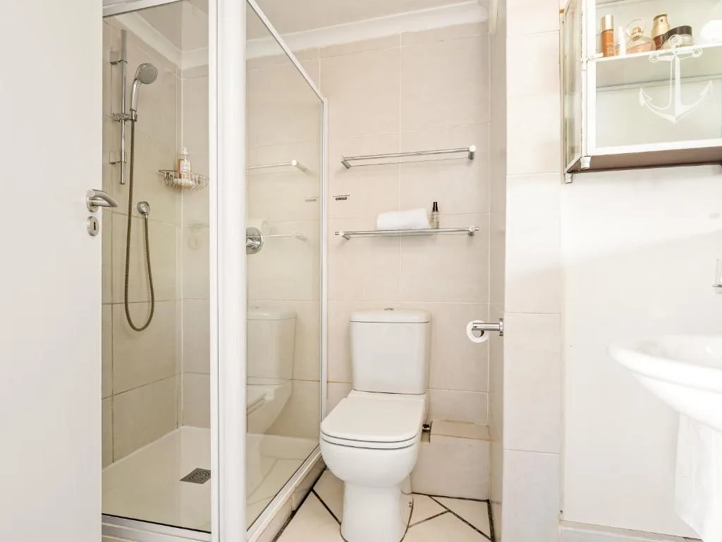 Clean modern bathroom with shower enclosure, toilet, and storage shelves