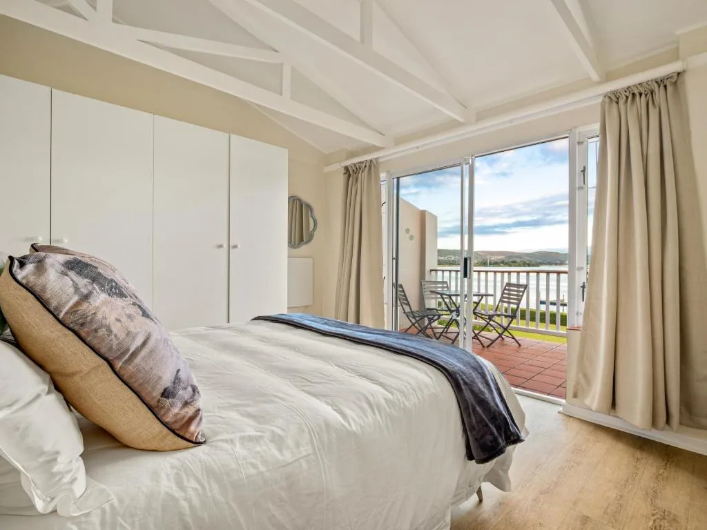 Spacious bedroom with bed, white wardrobe, and scenic mountain view through glass doors
