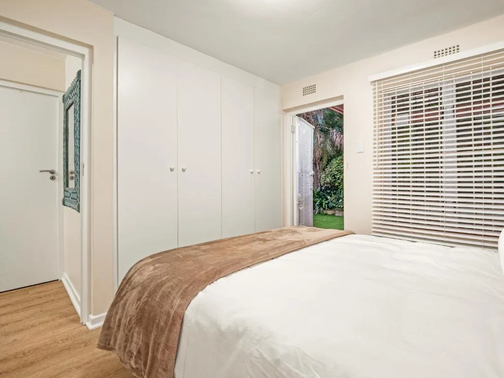 Bright bedroom with white built-in wardrobes and garden access doors