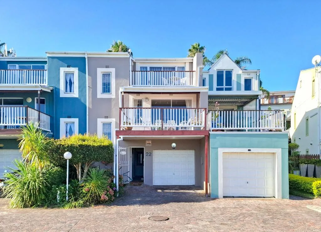 Colorful beachfront townhouse with balconies and garage, clear blue sky