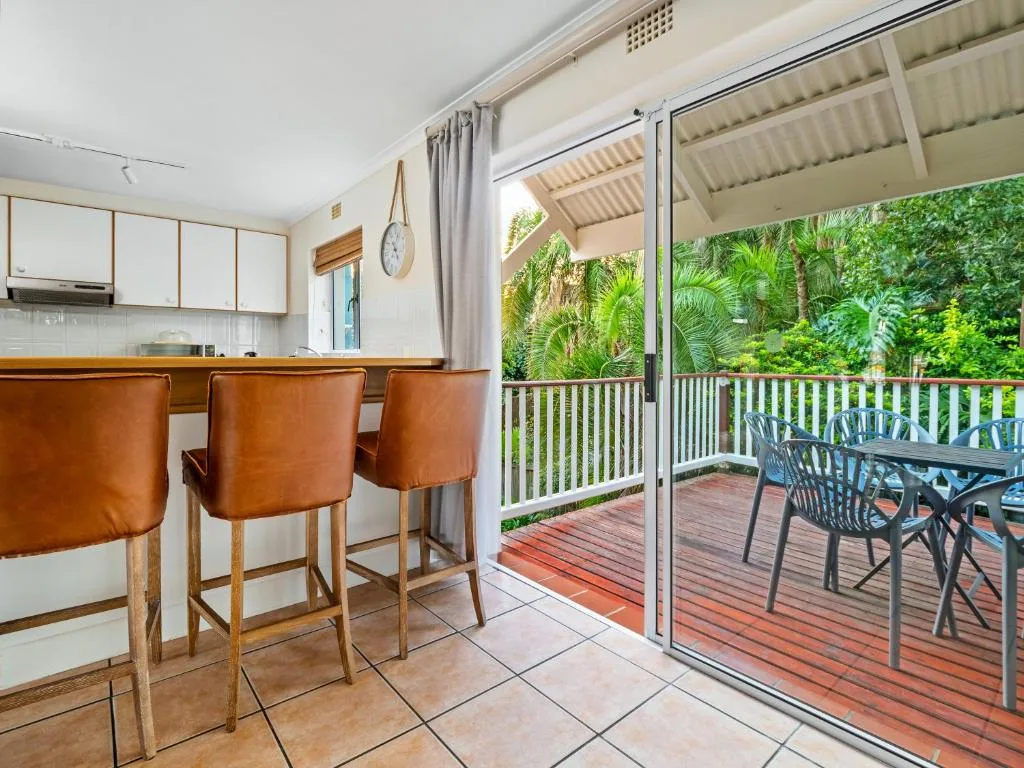 Open kitchen with island seating overlooking lush garden deck