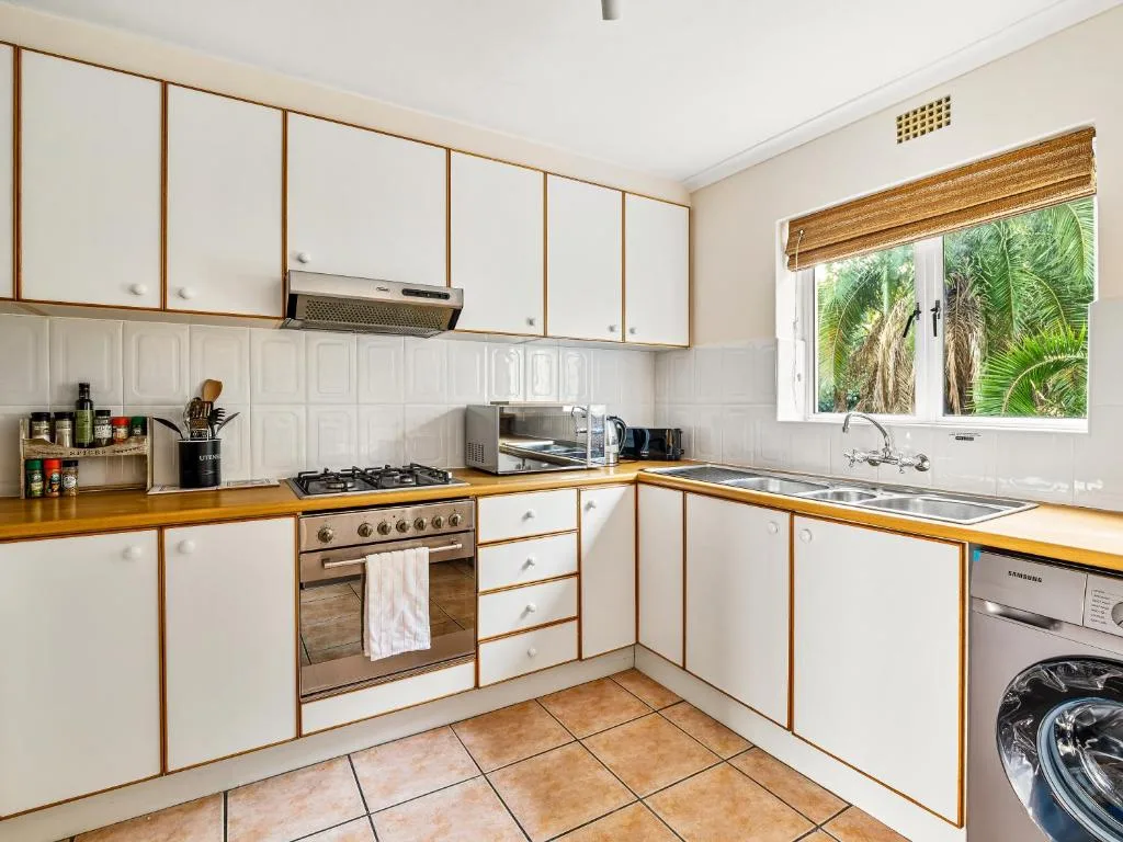 Well-equipped kitchen with cream cabinetry, gas stove, and tropical garden views