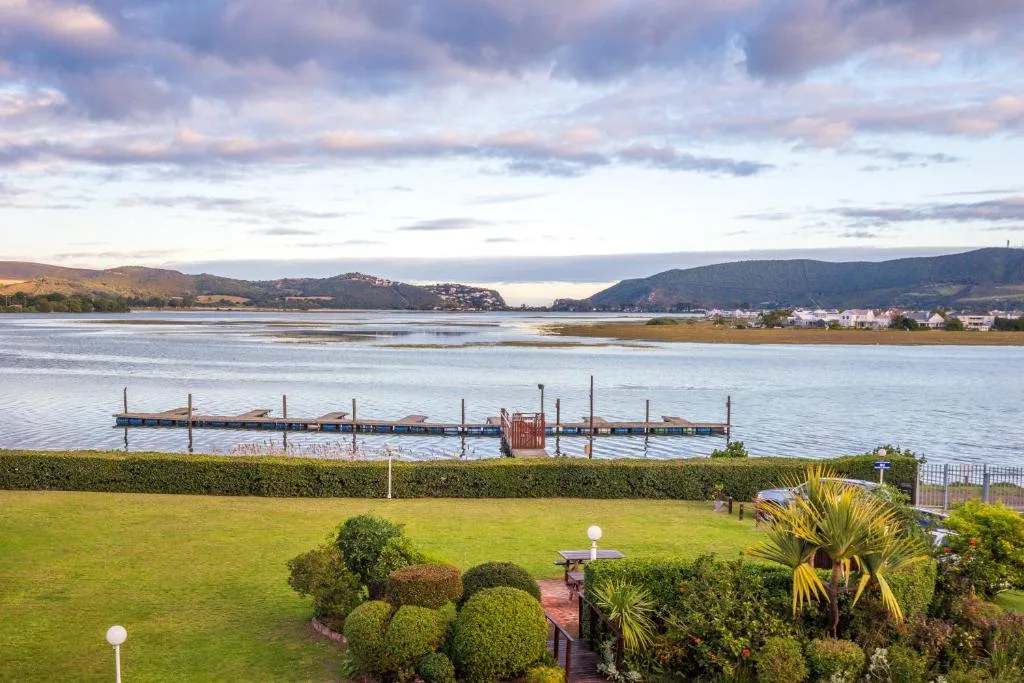 Scenic lagoon vista with mountains, jetty, and waterfront town beyond