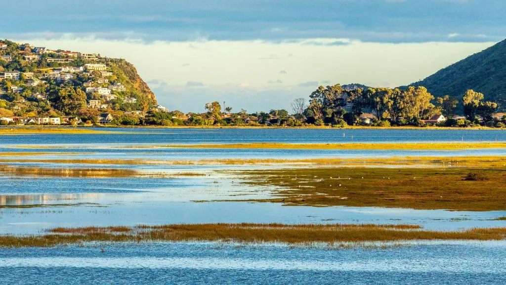 Scenic lagoon view with mountains, vegetation, and waterfront properties