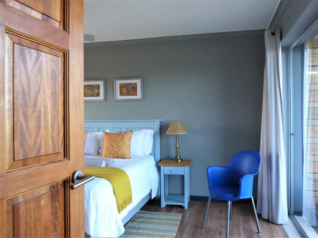 Bright bedroom with blue headboard bed, yellow throw, and blue chair