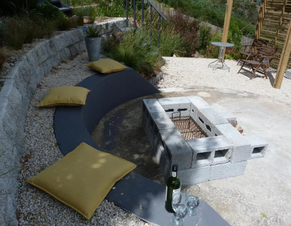 Outdoor seating area with cushioned loungers and built-in braai fire pit