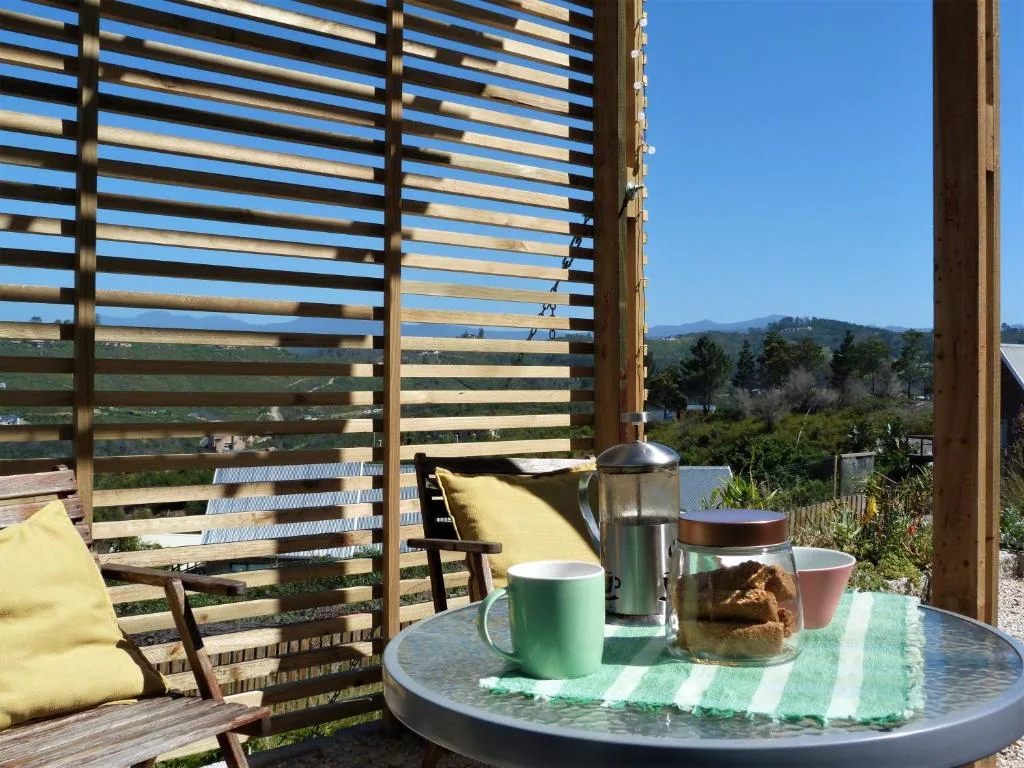 Wooden deck with table, chairs, and mountain views beyond slatted screen