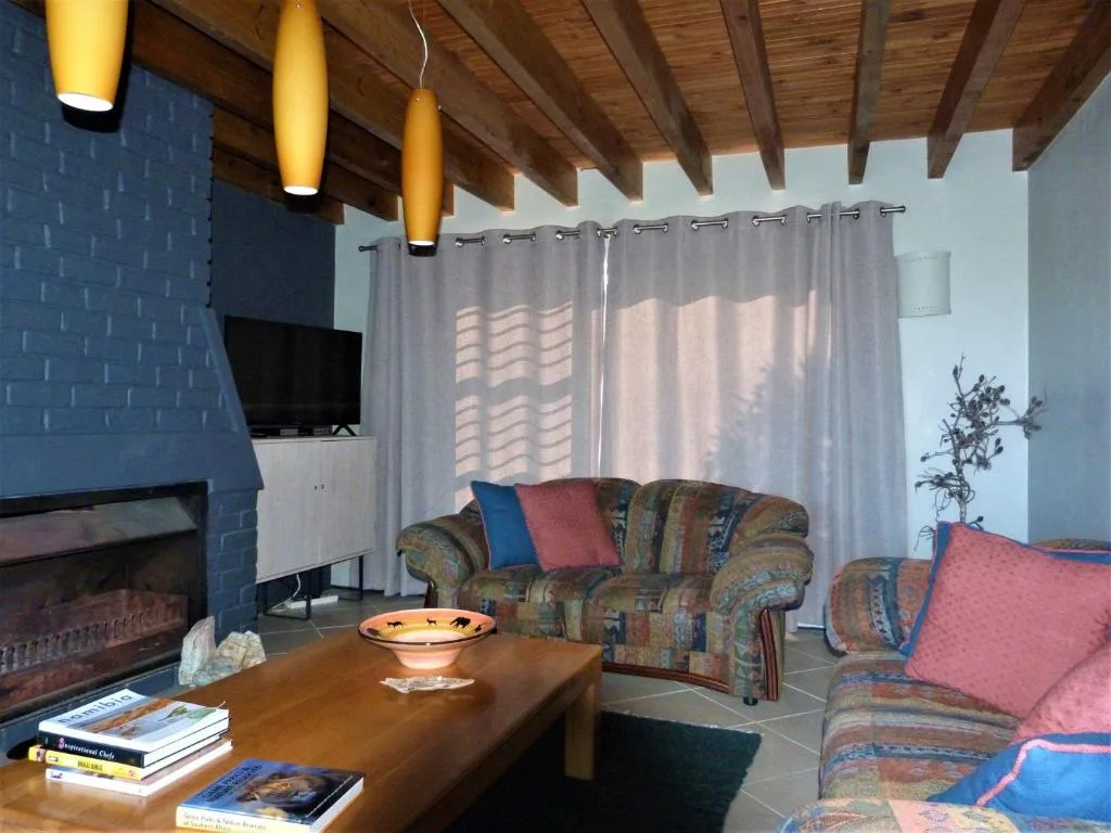Spacious living room with patterned sofas, fireplace, and wooden ceiling beams