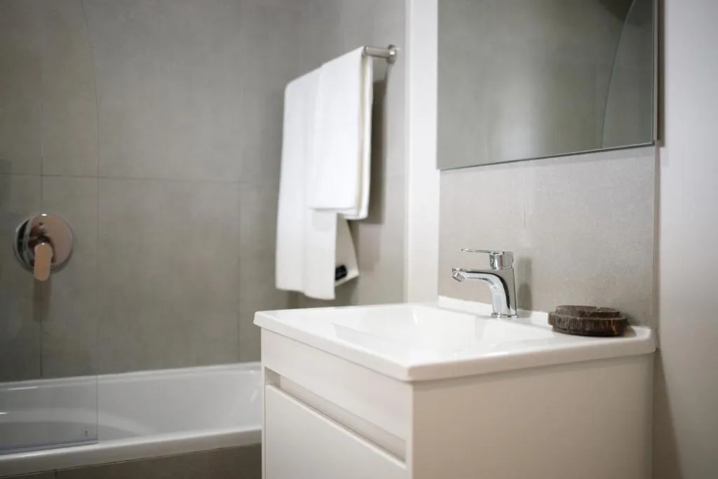 Modern bathroom with white vanity, mirror, and tiled shower area
