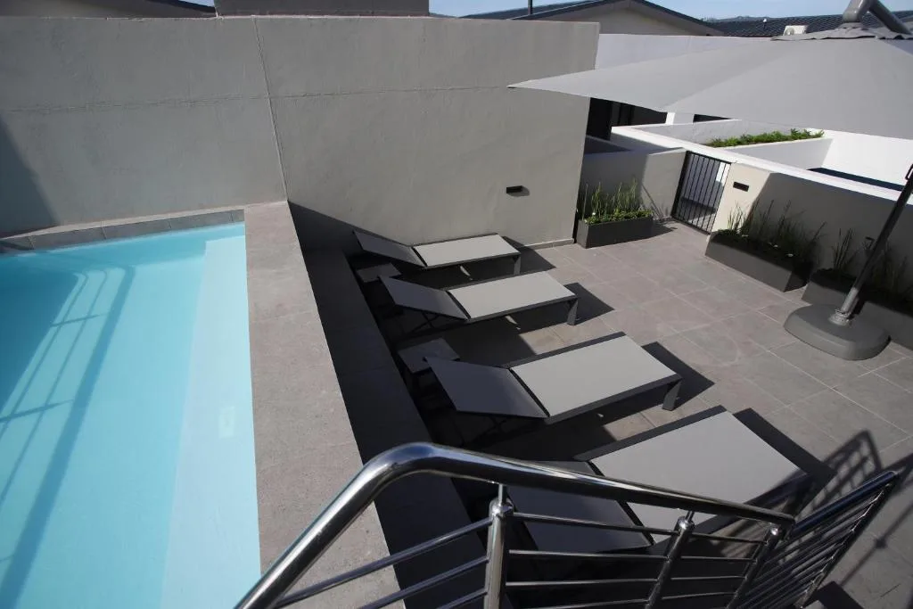Modern rooftop deck with loungers, pool, and contemporary architecture