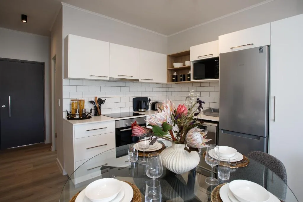 Modern white kitchen with stainless steel appliances and dining table setup