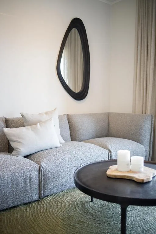 Modern living room with curved gray sofa, decorative mirror, and black coffee table