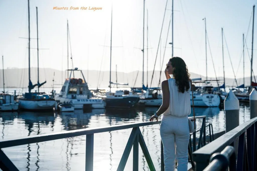 Woman gazing at sailboats moored in Knysna Lagoon from waterfront deck