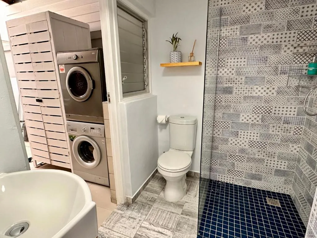 Modern bathroom with toilet, shower enclosure, and stacked washing machines