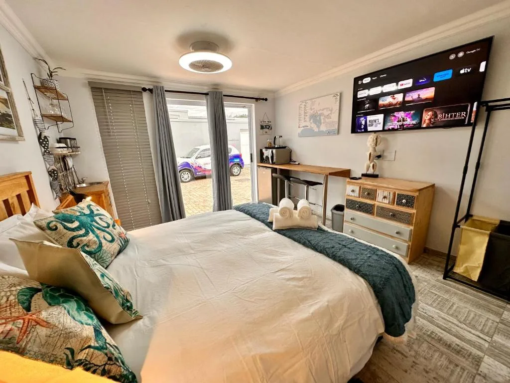 Bright bedroom with queen bed, smart TV, storage, and glass doors to driveway