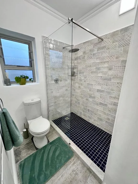 Modern bathroom with walk-in shower, patterned tiles, and white toilet