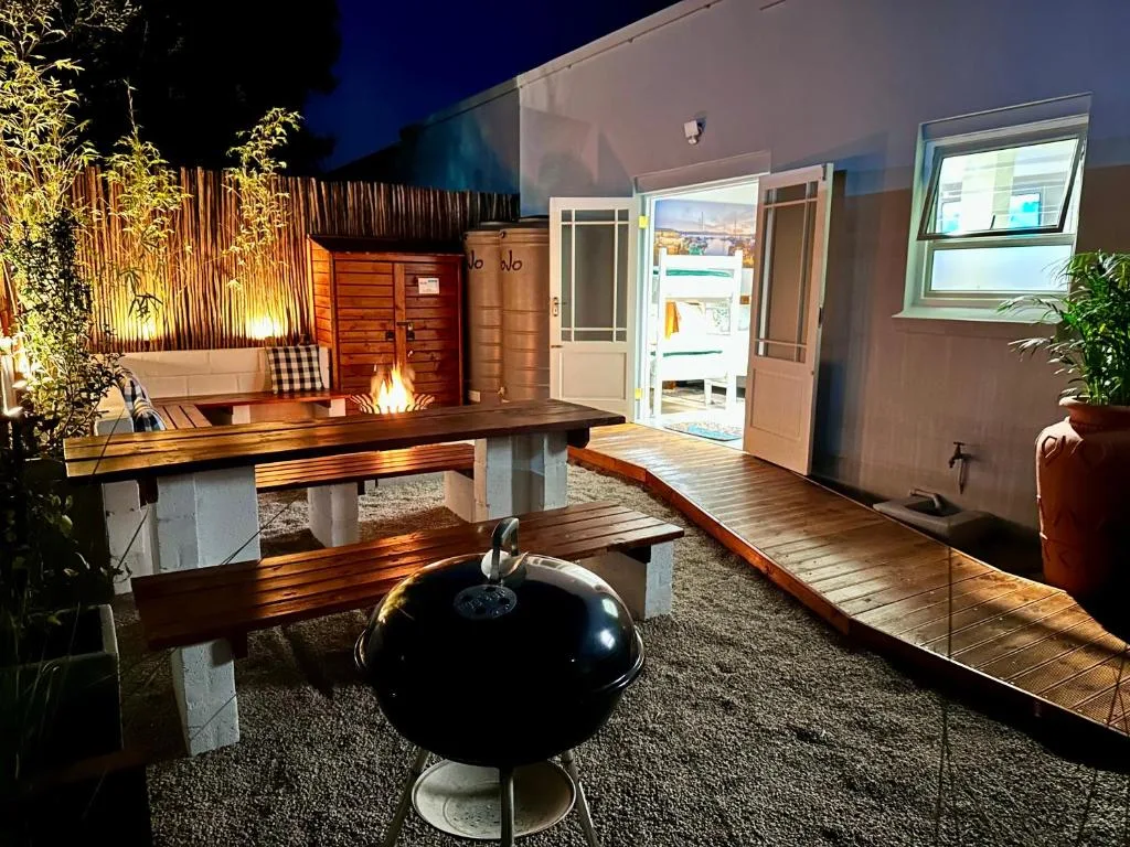 Evening patio with wooden benches, braai grill, and fire pit seating