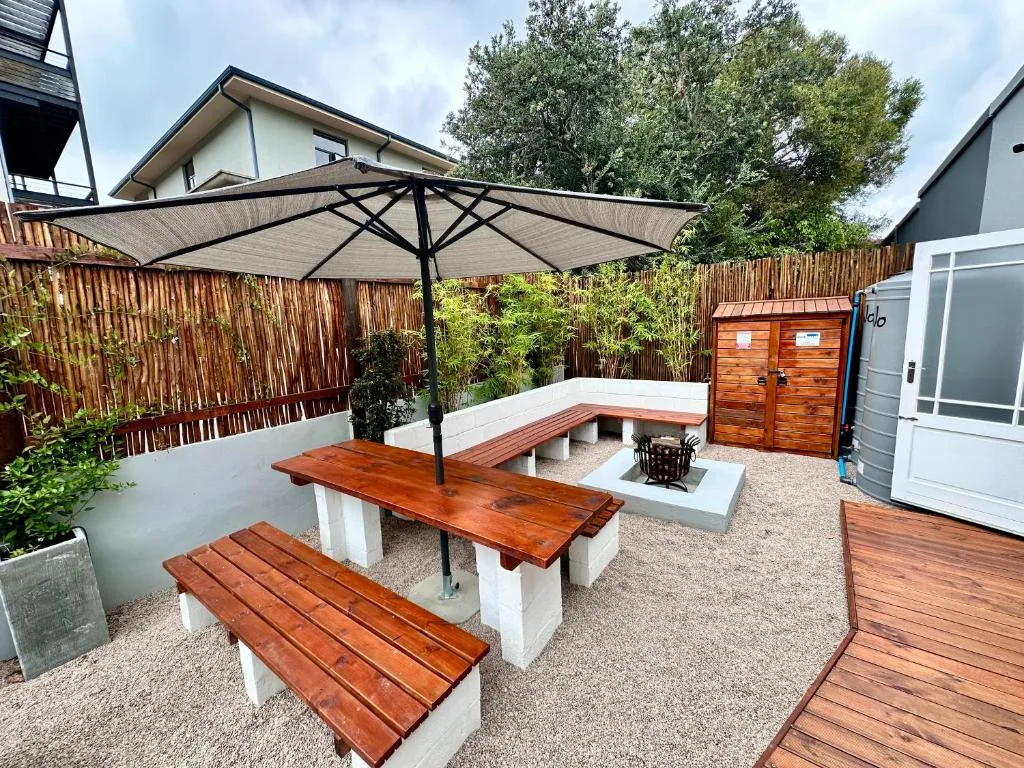 Outdoor patio with wooden picnic tables under large black umbrella