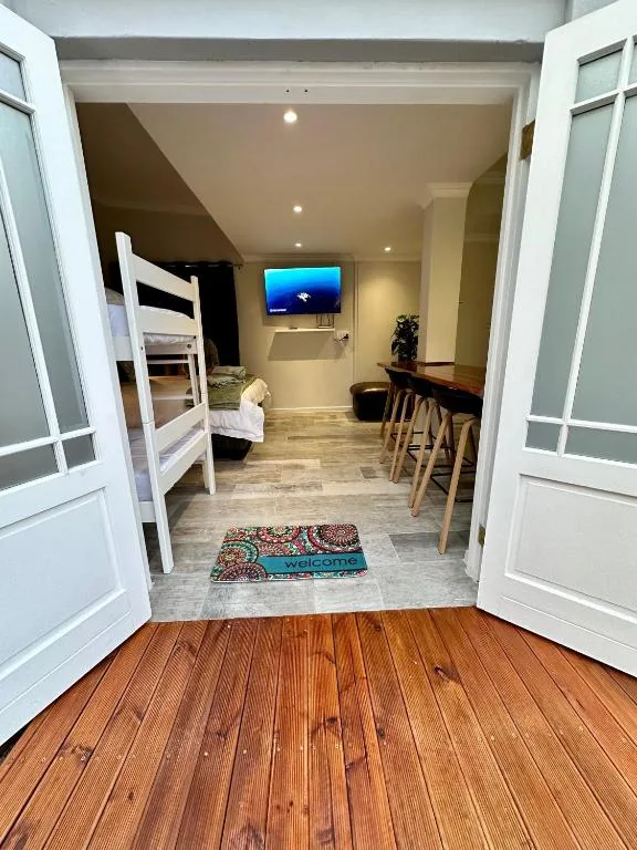 Open doorway revealing furnished studio apartment with welcome mat and seating
