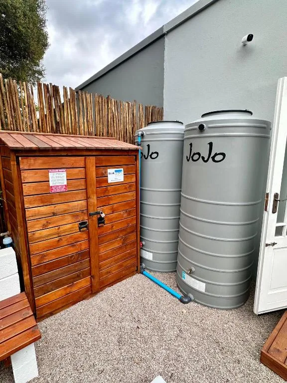 Wooden storage shed and metal water tanks outside property