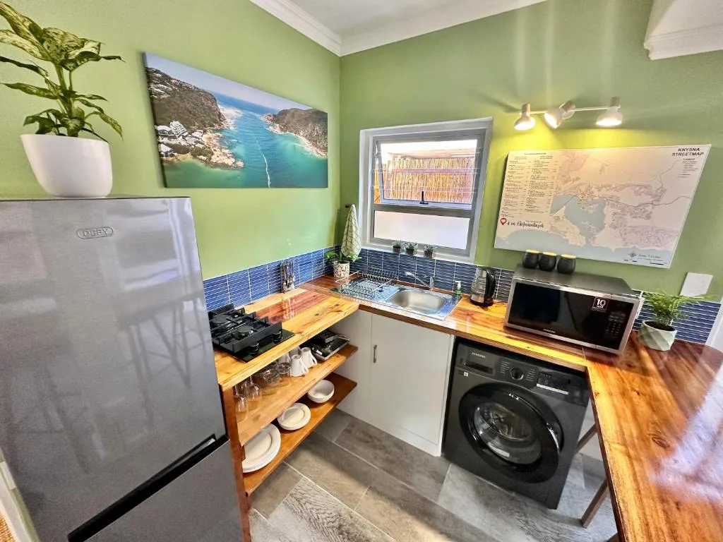 Bright green kitchen with wooden counters, stainless appliances, and coastal artwork