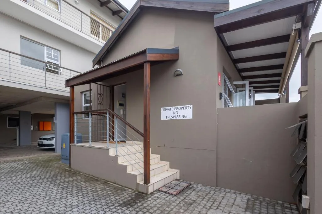 Modern townhouse entrance with wooden pergola and paved courtyard area