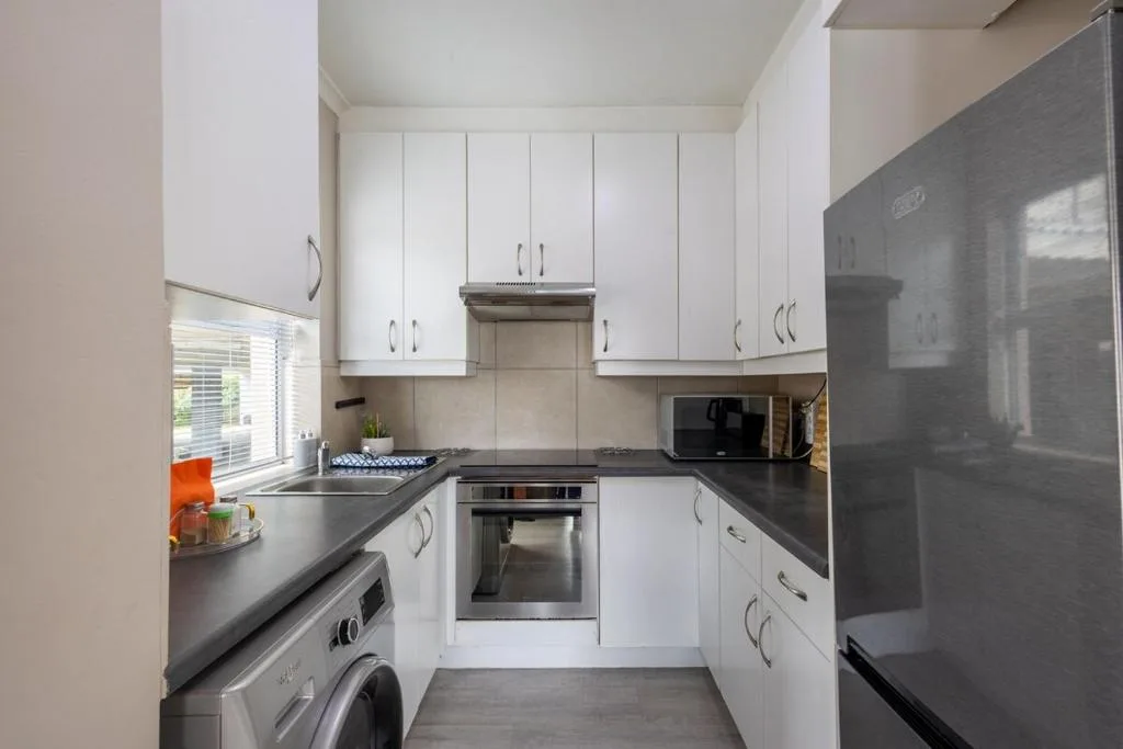 Modern kitchen with white cabinetry, dark countertops, and stainless steel appliances